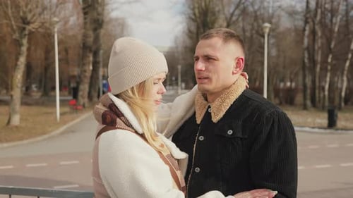 Happy couple in love having a good time in a winter park. Man and woman hugging and kissing.