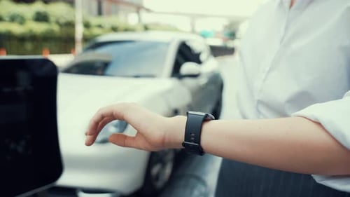 Woman Uses Smart Watch at Car Charging Station