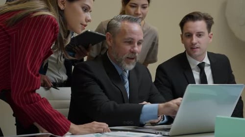 Adults Review Laptop Together in Bright Office
