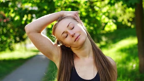Young Woman in Black Sportswear is Doing Neck Stretching Exercises in City Park Warm Up Before