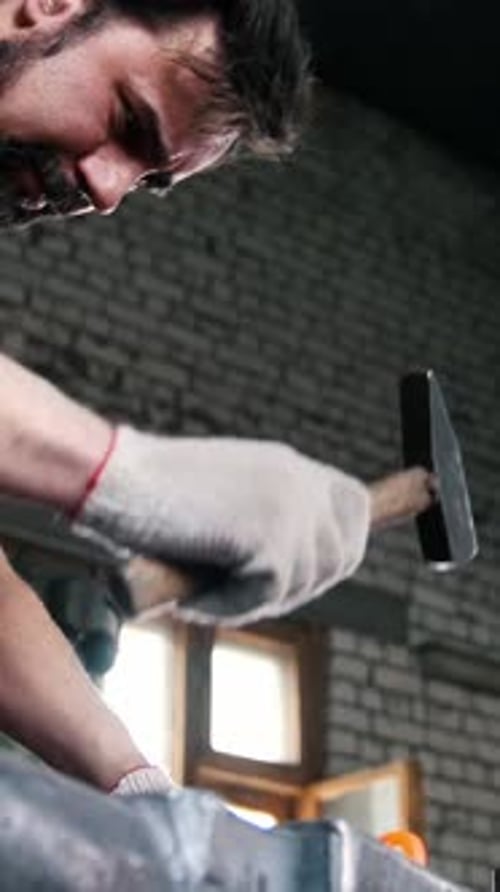 Concentrated Blacksmith Shaping Red-Hot Metal with Hammer