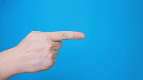 Male Hand Pointing a Finger to the Side Making a Hand Gesture Isolated on a Blue Background