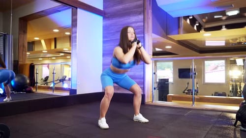 Brunette Woman Doing Squats at the Gym