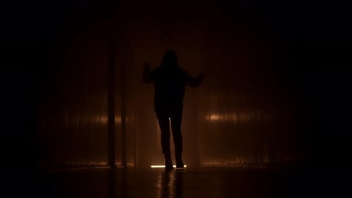 Silhouetted Figure Dancing in Dark Urban Corridor