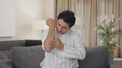 Man Applies Cream to Sore Arm at Home