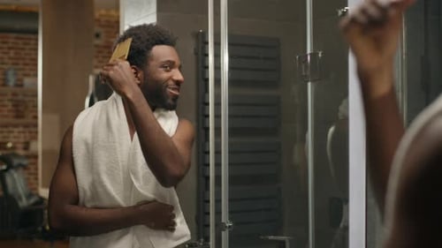 Smiling Man Combs Hair in Bathroom Mirror