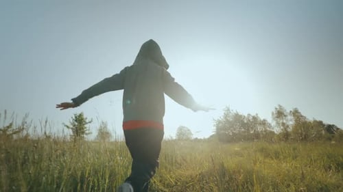 A criança corre pela grama com os braços levantados como um avião