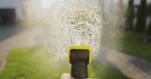 Man Spraying Green Grass Lawn with Sprayer Gardening Waters Growing and Plants Care