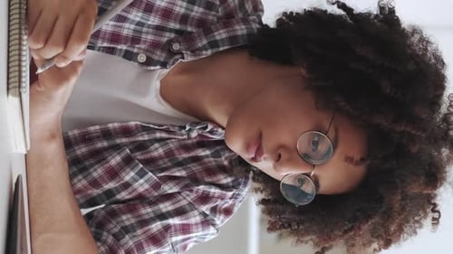 Young Adult Writing at Desk in Notebook