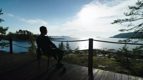 Man Sitting Calmly by the Lake Shore