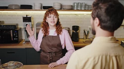 Cheerful Female Barista Talks to Visitor of Cozy Cafeteria