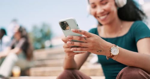 Hands, smartphone and woman typing outdoor, student on campus with communication and headphones