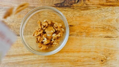 Walnuts Being Poured Into Glass Bowl Overhead