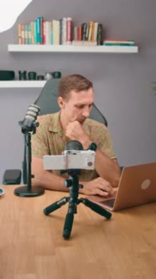 A Man in a Professional Studio is Using a Laptop and Microphone to Record a Podcast