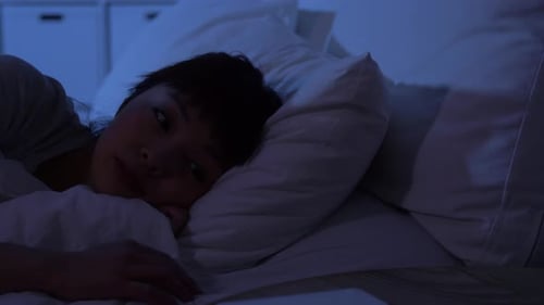 Young Woman Using Phone in Bed at Night