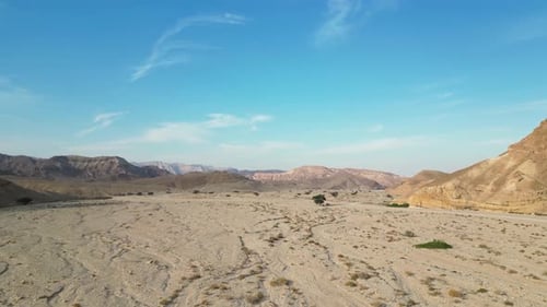 An open view of a desert valley with a clear blue sky captured by a drone