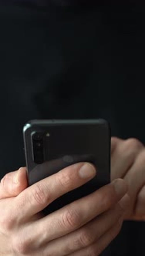 Homme utilisant un smartphone Utilisateur de smartphone sur fond sombre Vidéo verticale