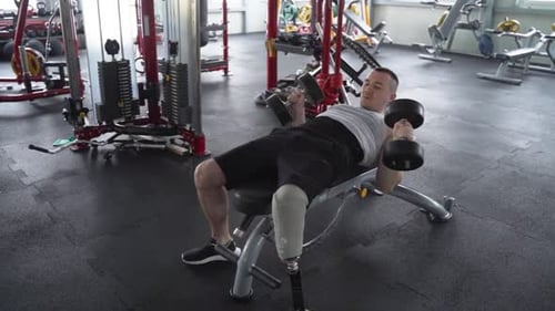 Determined male with prosthetic leg finish excercice and drops weights on the floor at the gym