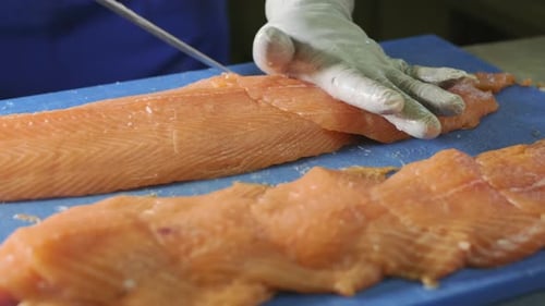 Close up of Professional chef hand using fish fillet knife slice fresh orange salmon meat on cutting