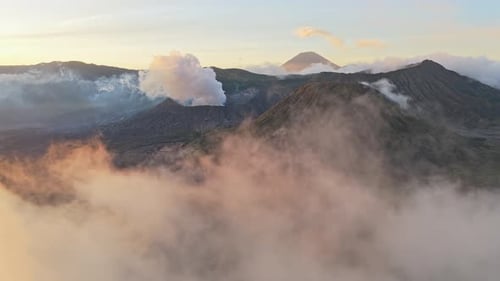 Aerial view revealing smoking volcanoes at sunrise