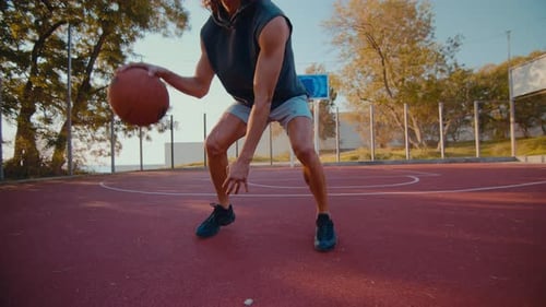 Young Sportsman Skillfully Dribbles Ball on Modern Court