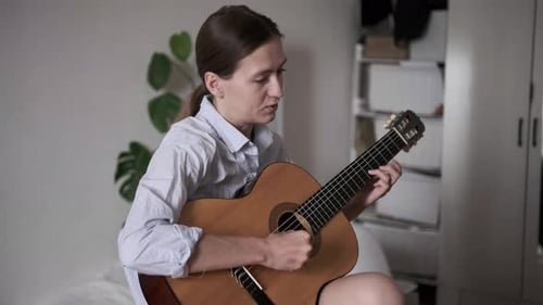 Woman Playing Guitar and Singing in Bedroom