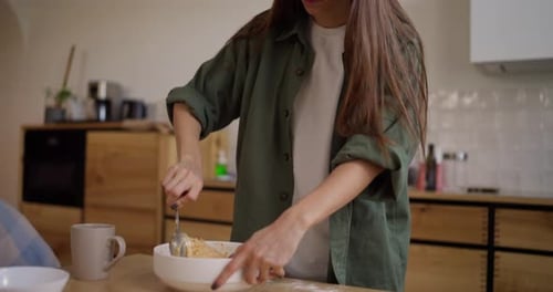 Young Woman Mixing Batter in Bowl in Kitchen