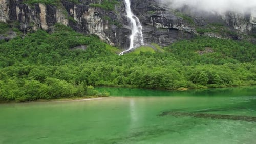 Waterfall and green lake in the mountains of Norway