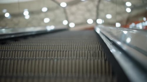 CloseUp of Moving Escalator with Glass Frame and Bokeh Light Background