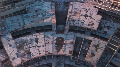 Sobrevuelo aéreo: complejo circular de concreto abandonado, ruinas de construcción inacabada al atardecer