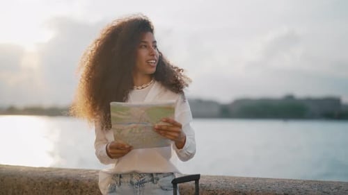 Young Woman Holding Map Near Water