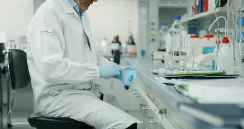 Scientist Puts On Gloves in Bright Laboratory