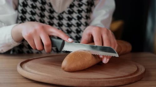 Slicing Baguette Bread with Knife on Cutting Board