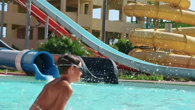 Scared and happy kid sliding in a water slide at Water Amusement Park ...