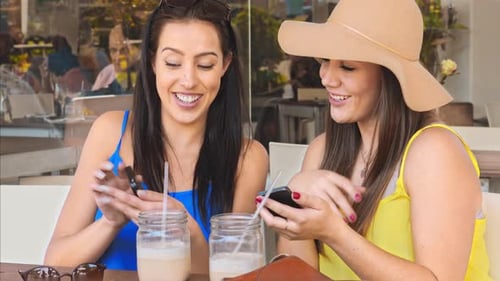 Two Young Women Chatting and Using Mobile Phones