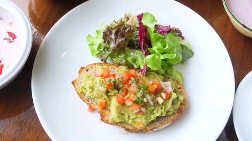 Healthy Vegan Breakfast in Cafe with Avocado Toast on Plate