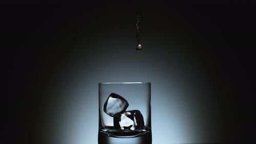 Close-Up of Liquor Pouring Over Ice Cubes in Glass