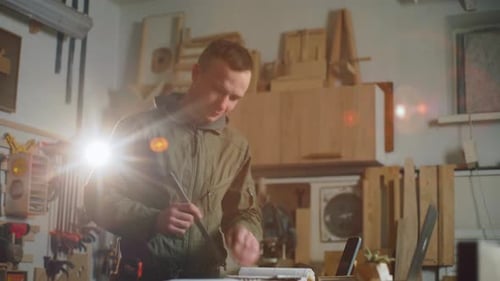 Man Measures Technical Drawing in Bright Workshop
