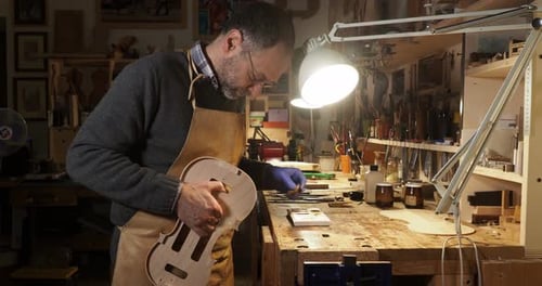 Luthier violinmaker artisan tamponing violin ribs in his workshop in Cremona, Italy