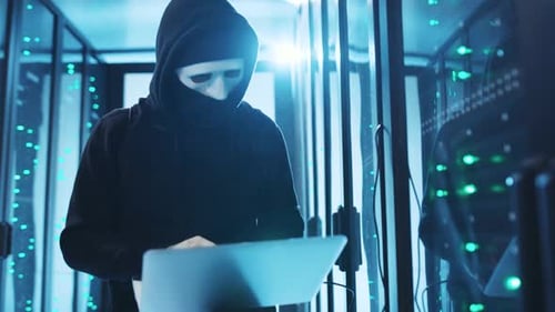 Ein mysteriöser Hacker mit Maske wird in einem Rechenzentrum gesehen, wie er heimlich einen Laptop benutzt