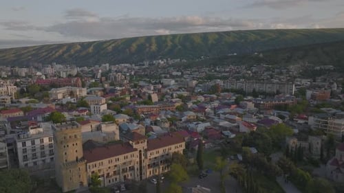 Aerial flight over beautiful capital city of Tbilisi with mountains in background