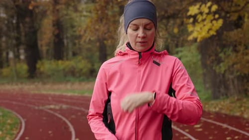 Female Runner Prepares to Run Puts on Sports Clothes on the Stadium Treadmill