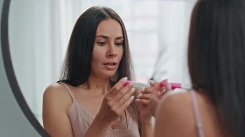 Woman Reacts to Pregnancy Test in Bathroom Mirror