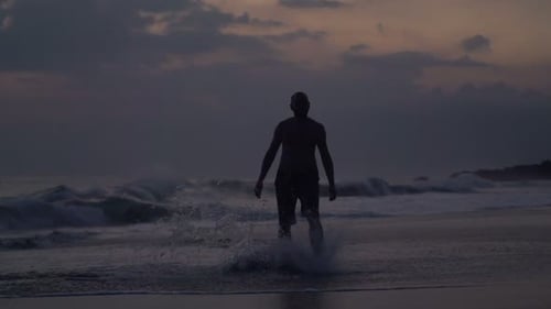 Silhouette of Man Walking Near Sea and Splashing Water in Evening, Super