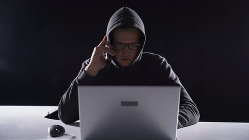 Hooded Hacker Working at Night on Computer
