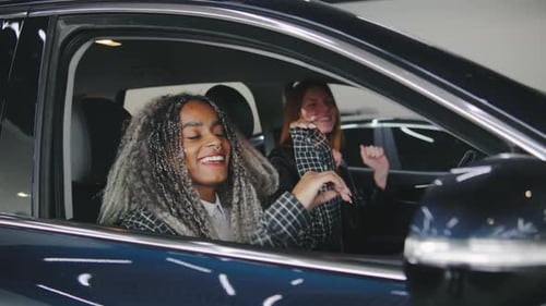 Two Happy Young Women Dancing in a Car