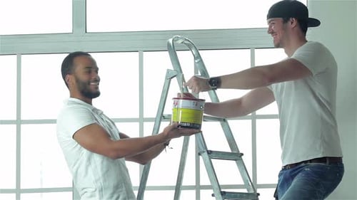 Men passing paint can on ladder together