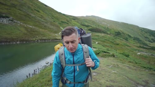 Portrait of a Man with a Backpack Walking Next to a Lake in the Mountains