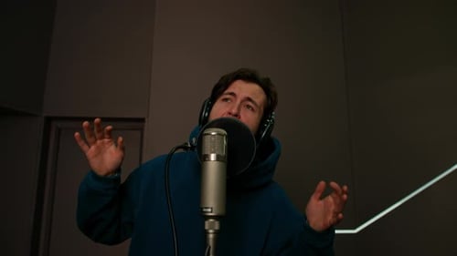 singer with headphones and microphone emotionally recording a new song in a professional studio