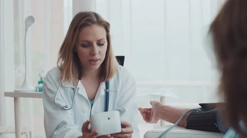 Female Doctor Explains Blood Pressure Machine to Patient